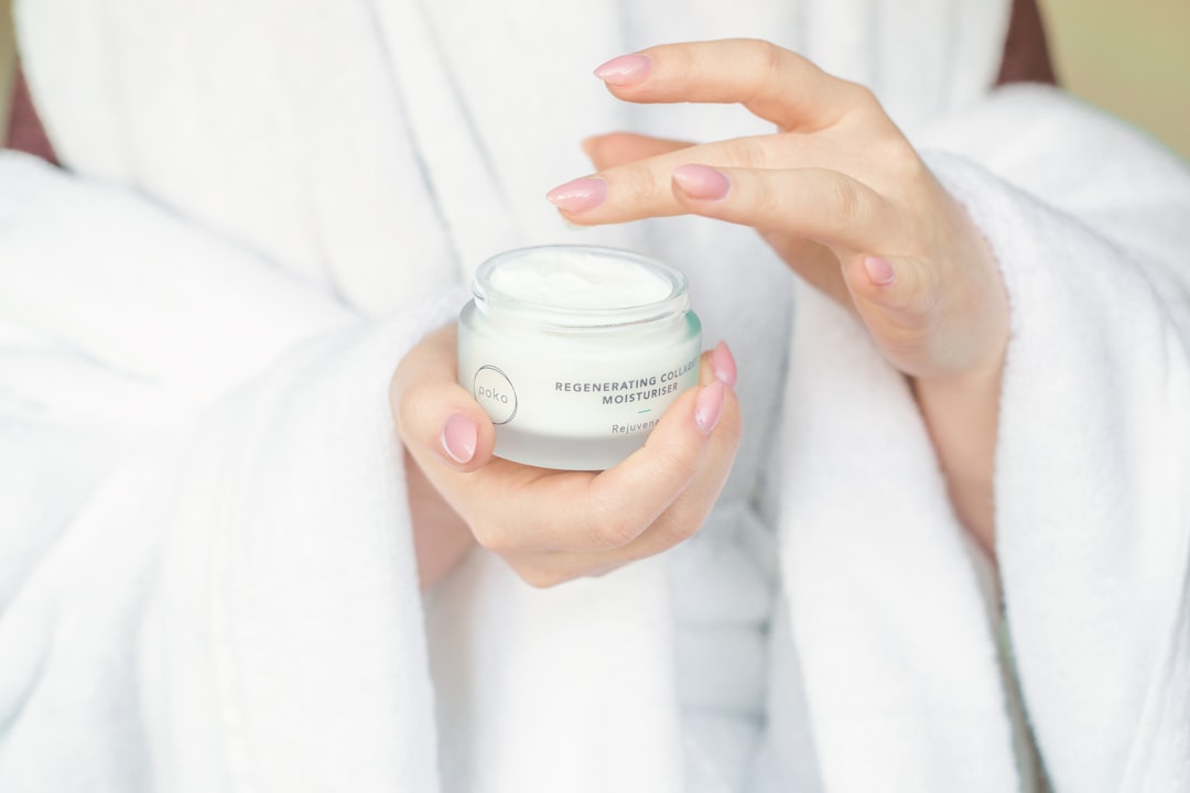 Detalle de una crema facial con CBD junto a hojas de cáñamo frescas y un frasco de sérum en un baño luminoso.