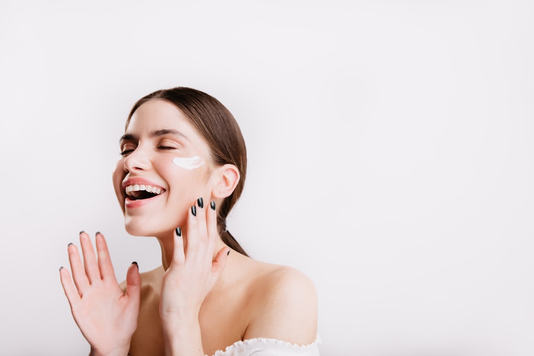 Mujer aplicando crema enriquecida con CBD en su rostro, disfrutando de los beneficios de los cannabinoides para una piel sana y equilibrada.