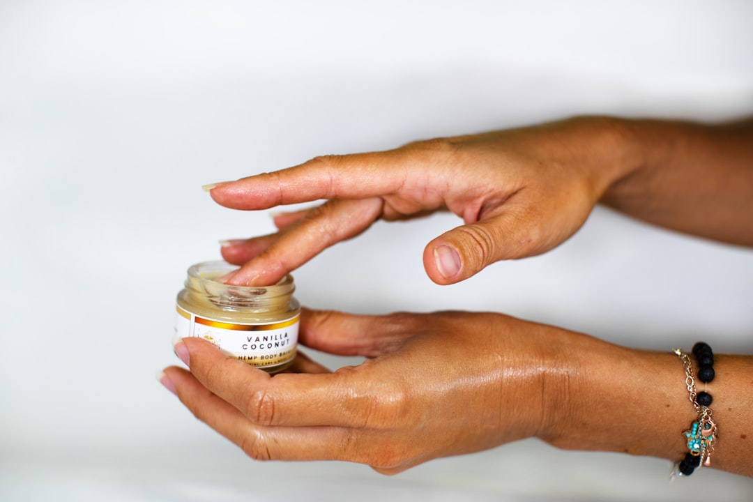 Manos aplicando bálsamo de CBD en la piel, mostrando los beneficios del CBD tópico para el bienestar localizado y natural.