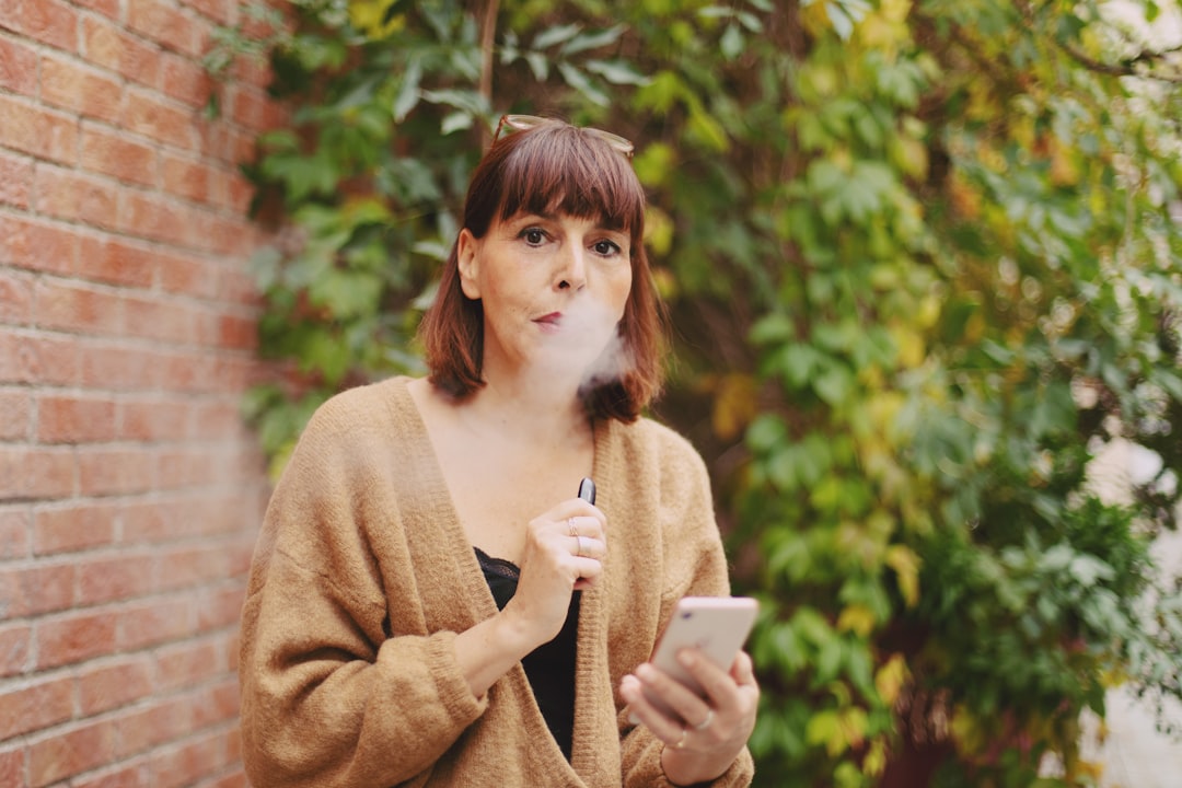 Gros plan sur une personne vapant de l'e-liquide CBD avec un pod mod, affichant une expression de sérénité et de calme, pour une vape relaxante.