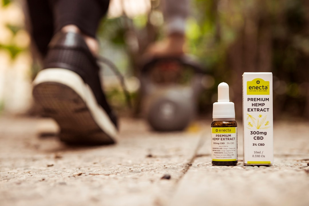 Deportista aplicando aceite de masaje CBD en la pierna, con un fondo de paisaje mediterráneo español, para la recuperación muscular.