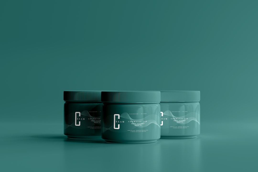 Flacons et pots de crèmes CBD et huiles de massage posés sur une table en bois clair, illustrant la diversité des produits CBD externes.