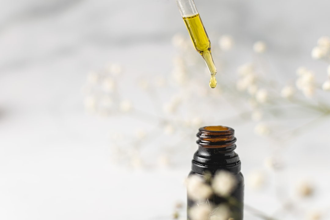 Frasco de aceite de CBD y crema facial con ingredientes naturales sobre una superficie de madera, destacando el cuidado para pieles reactivas.